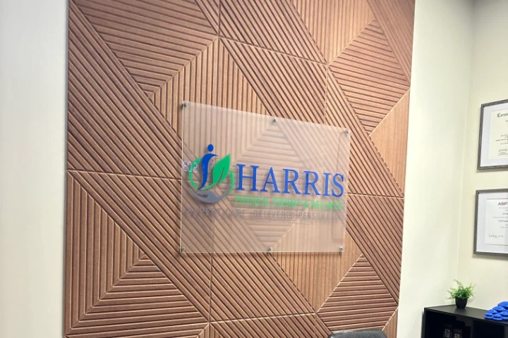 The Harris Physical Therapy and Wellness sign on the wood slat wall in the clinic waiting area