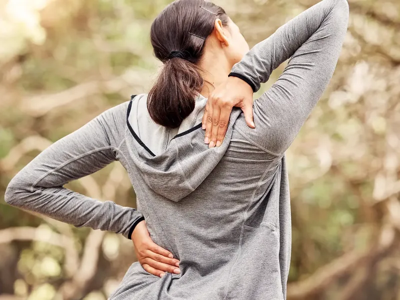 A person pressing a hand into their lower back where the pain sits