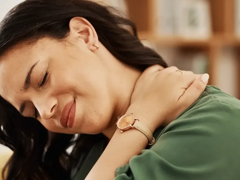 A woman holding the side of her neck and shoulder, worn down by pain that has not let up