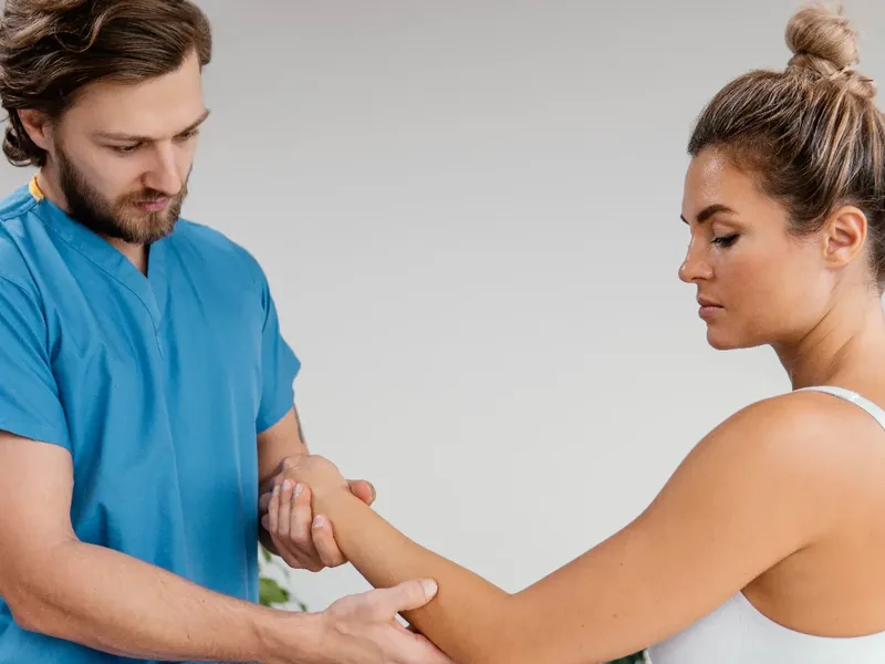 A therapist guiding a patient through controlled elbow range of motion